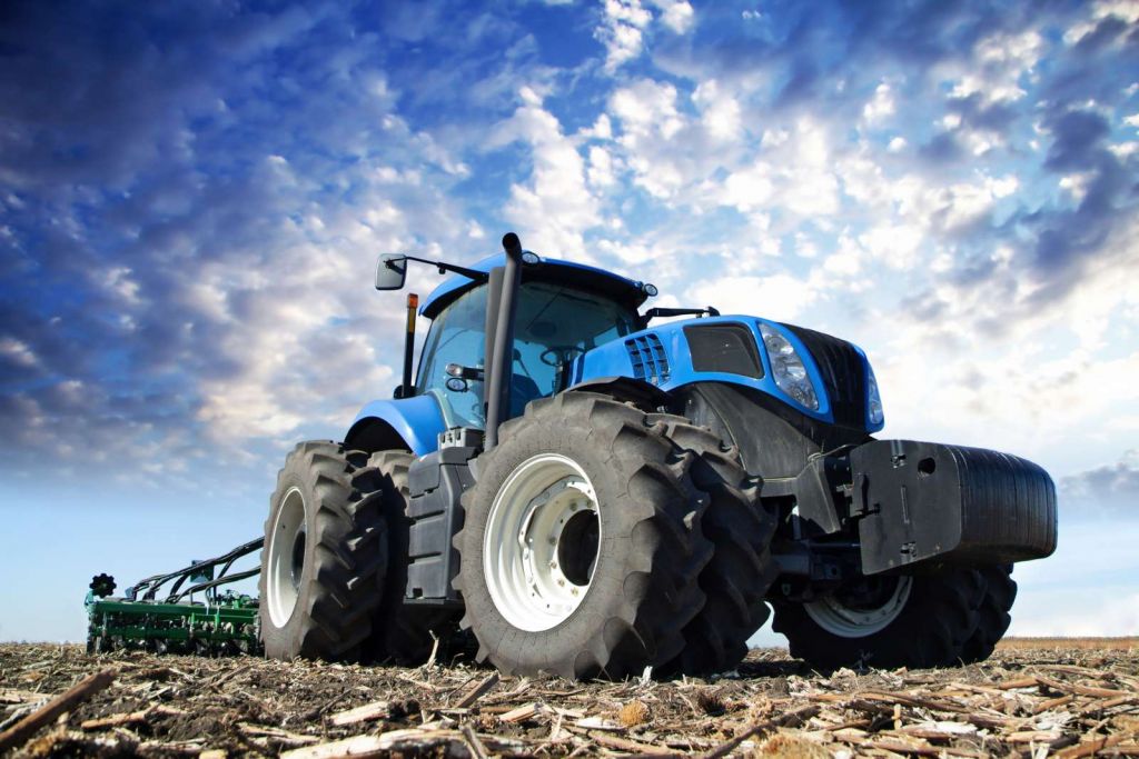 Grote blauwe tractor onder een bewolkte hemel
