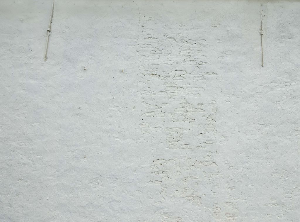 Wall with white stucco and wall anchors
