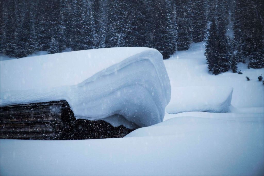 Snow-covered alpine hut in winter storm