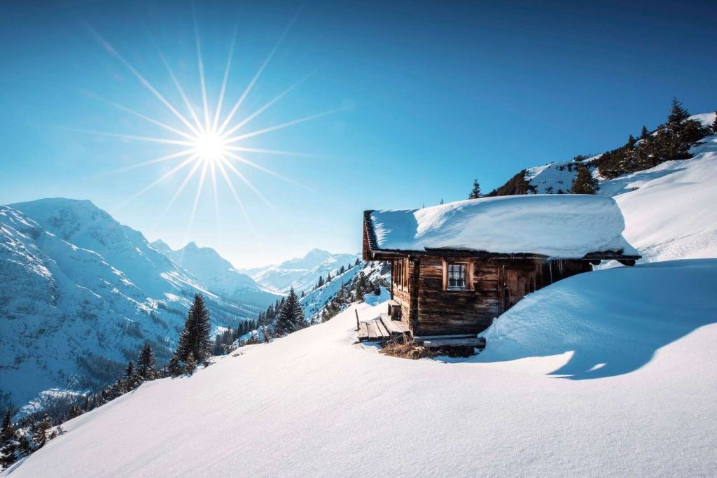 Winter sun above wooden mountain hut