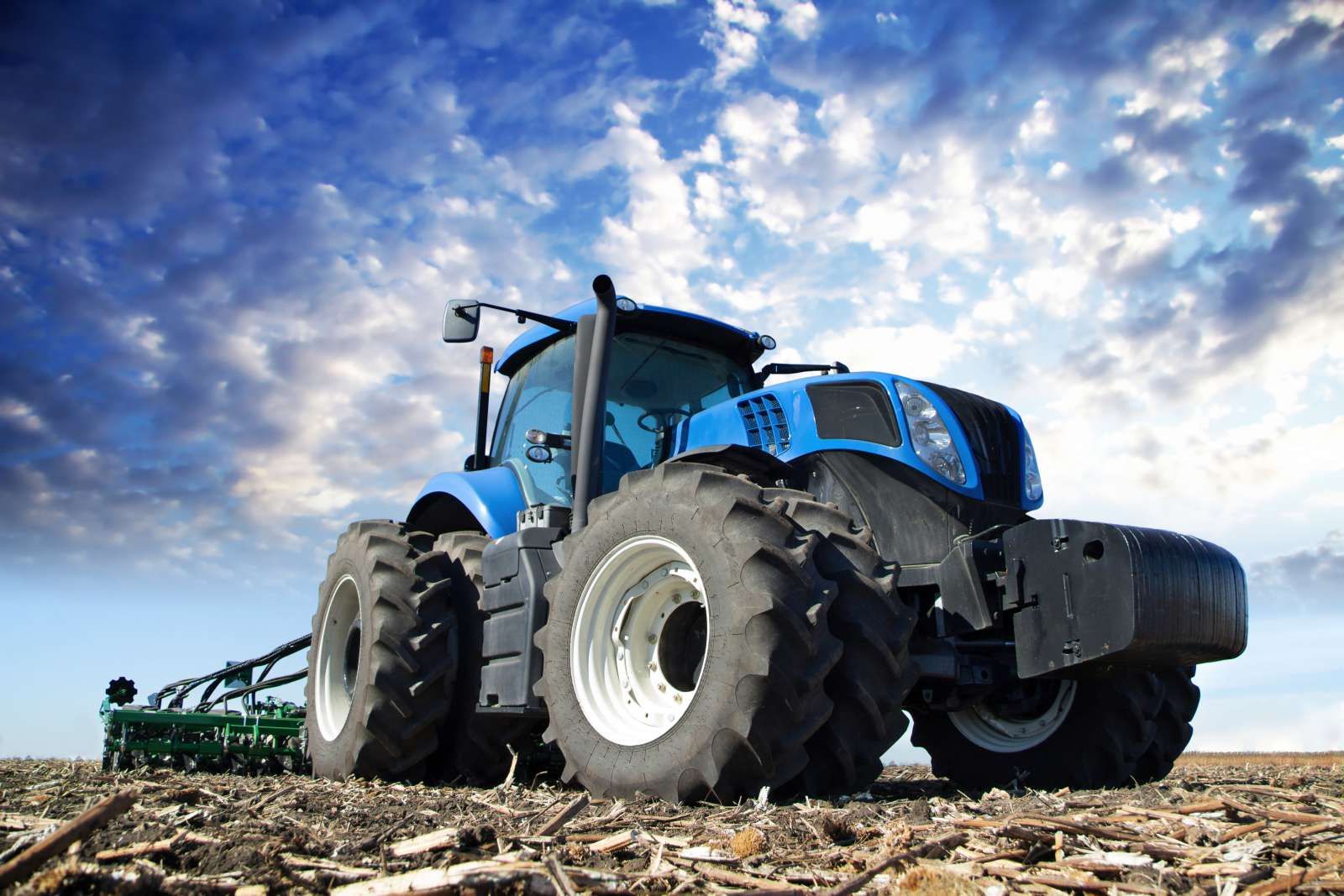 Grote blauwe tractor onder een bewolkte hemel