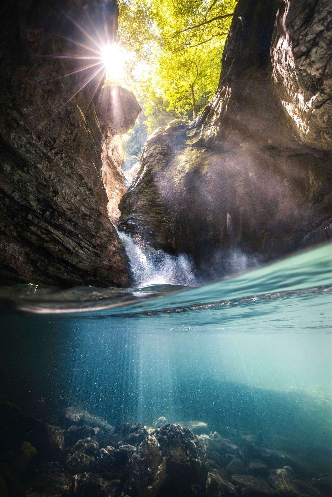 Sunlight in mountain gorge with waterfall