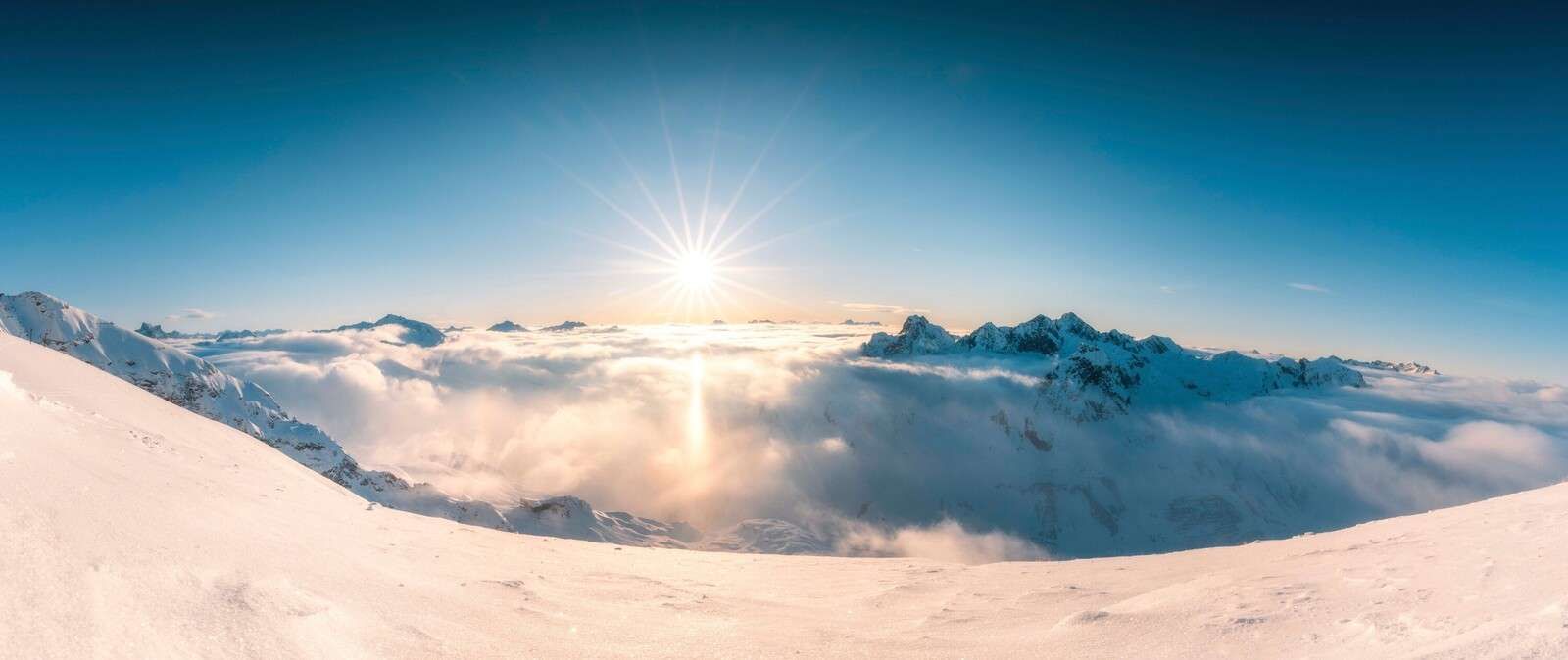 Sun above cloud cover in alpine panorama
