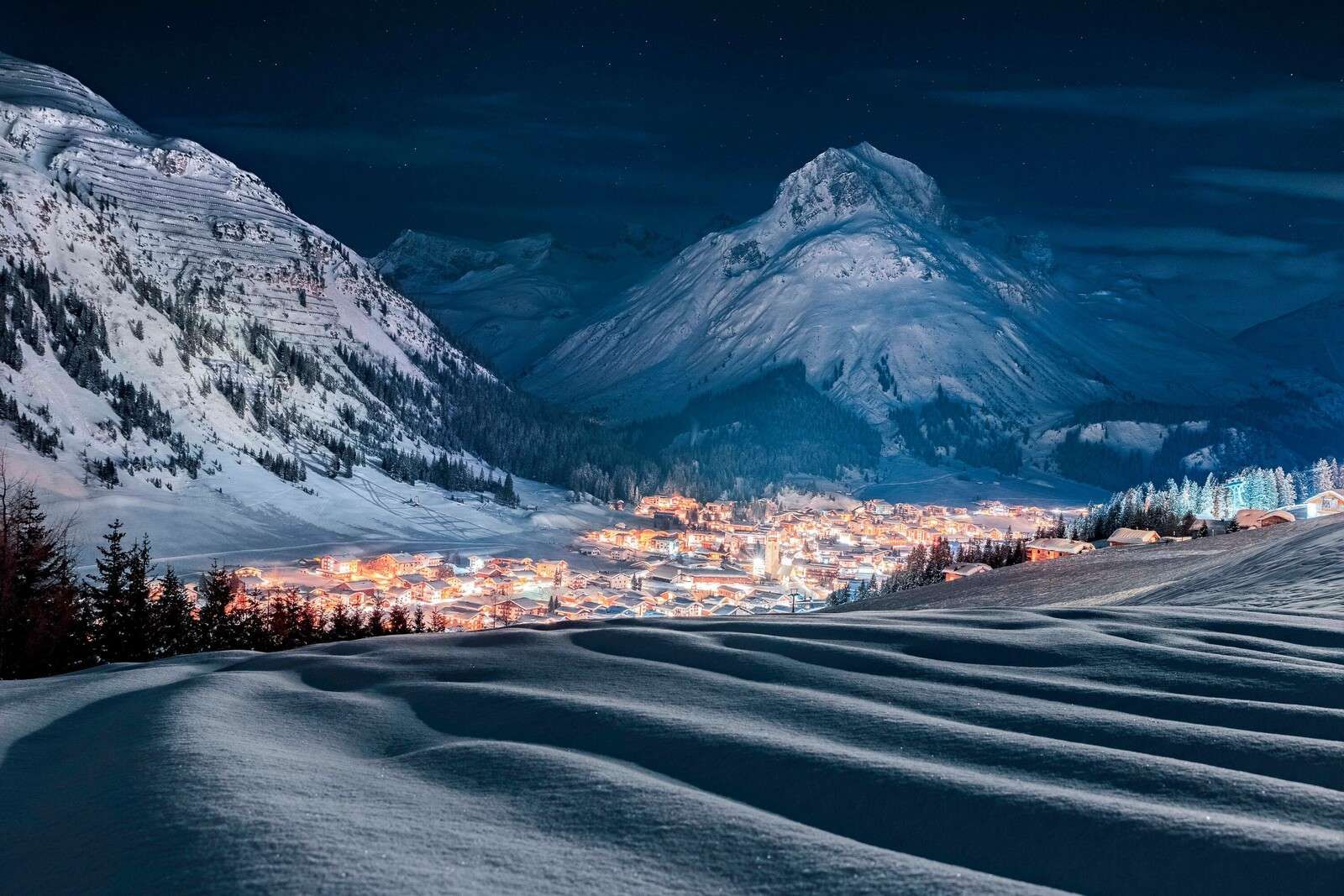 Winter village under moonlight in alpine valley