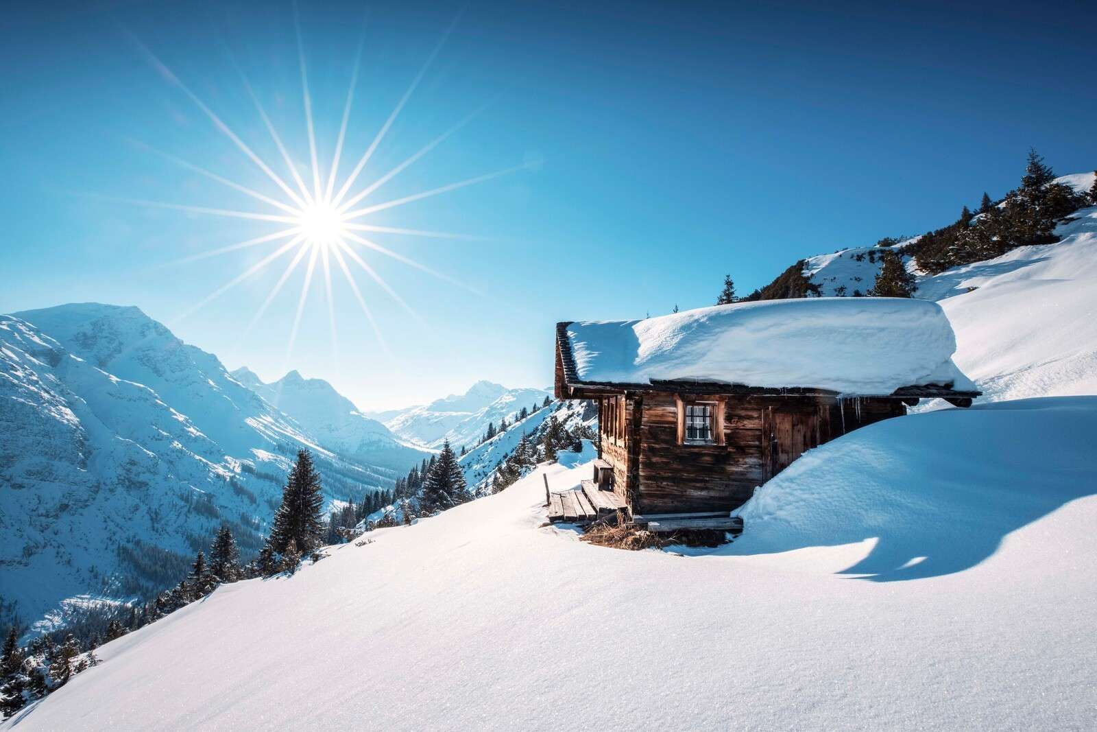Winter sun above wooden mountain hut