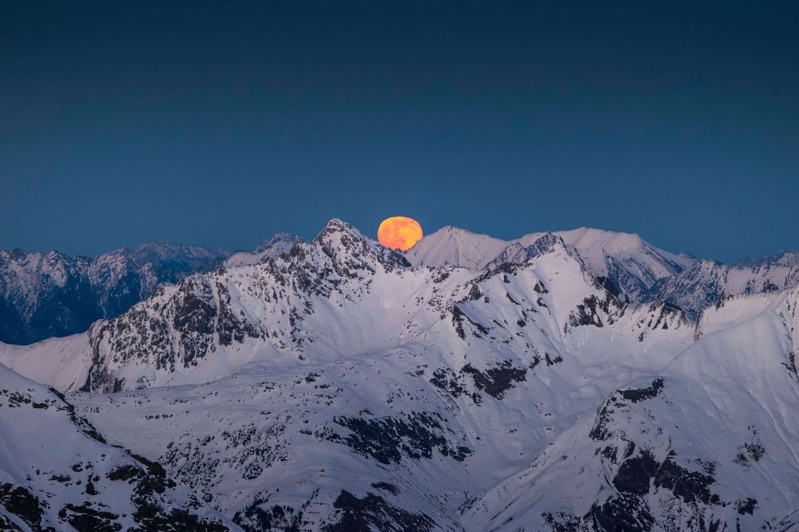 Full moon above alpine peaks
