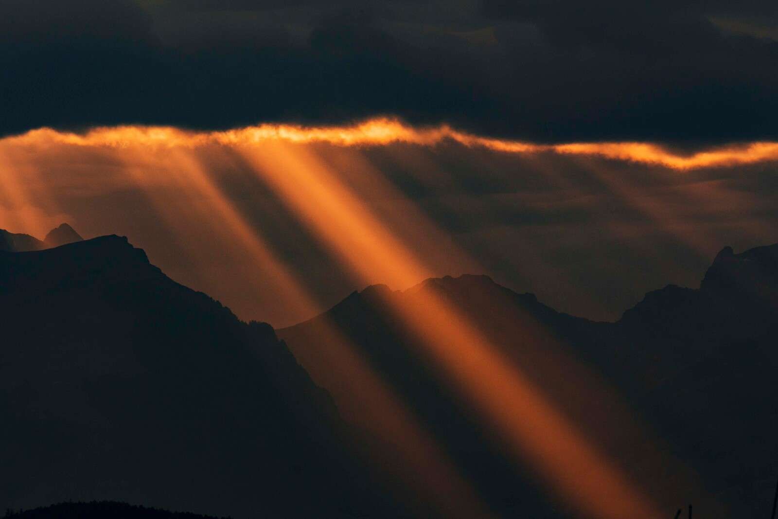 Golden sunbeams over mountain silhouette