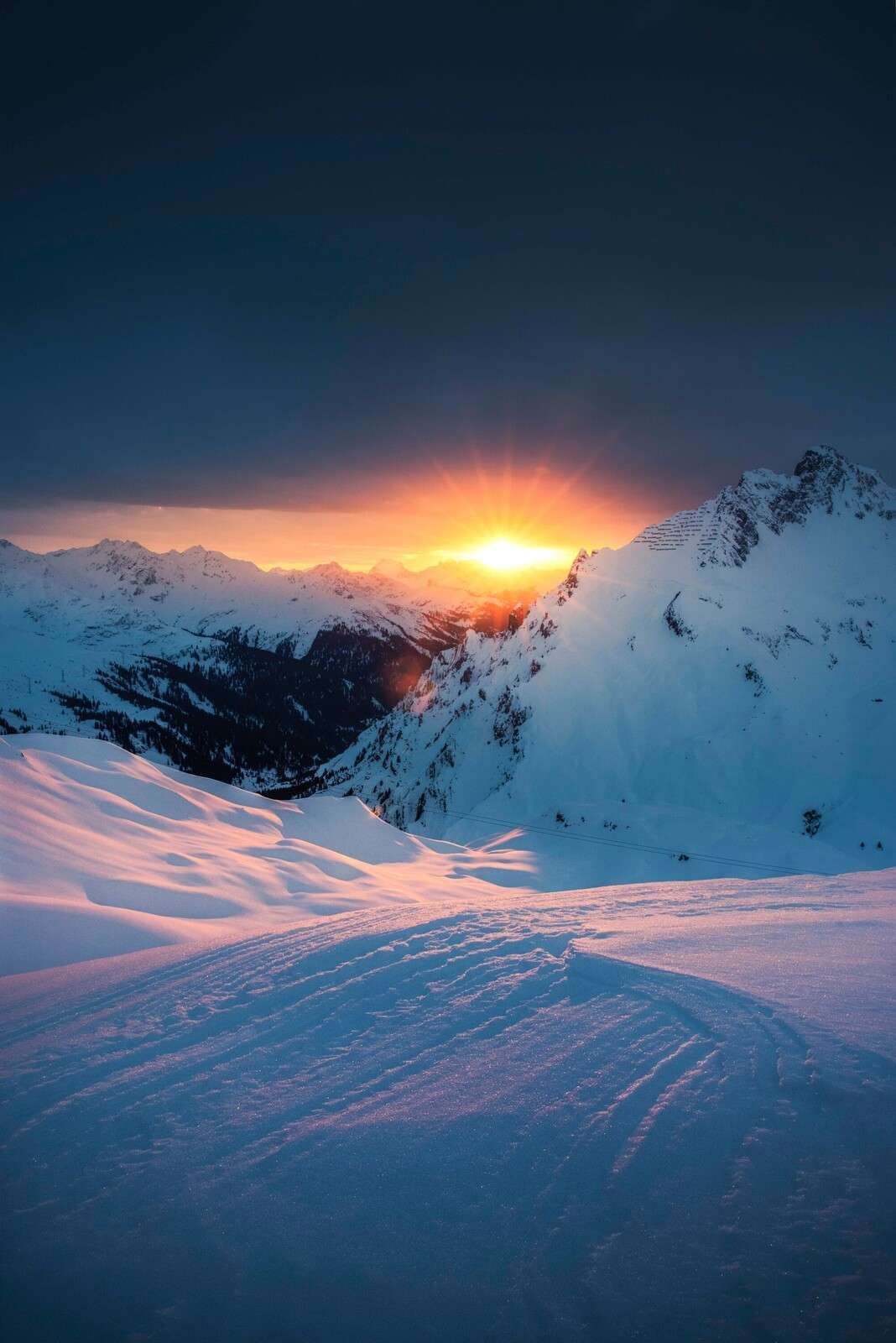 Setting sun above snow-covered alpine peaks