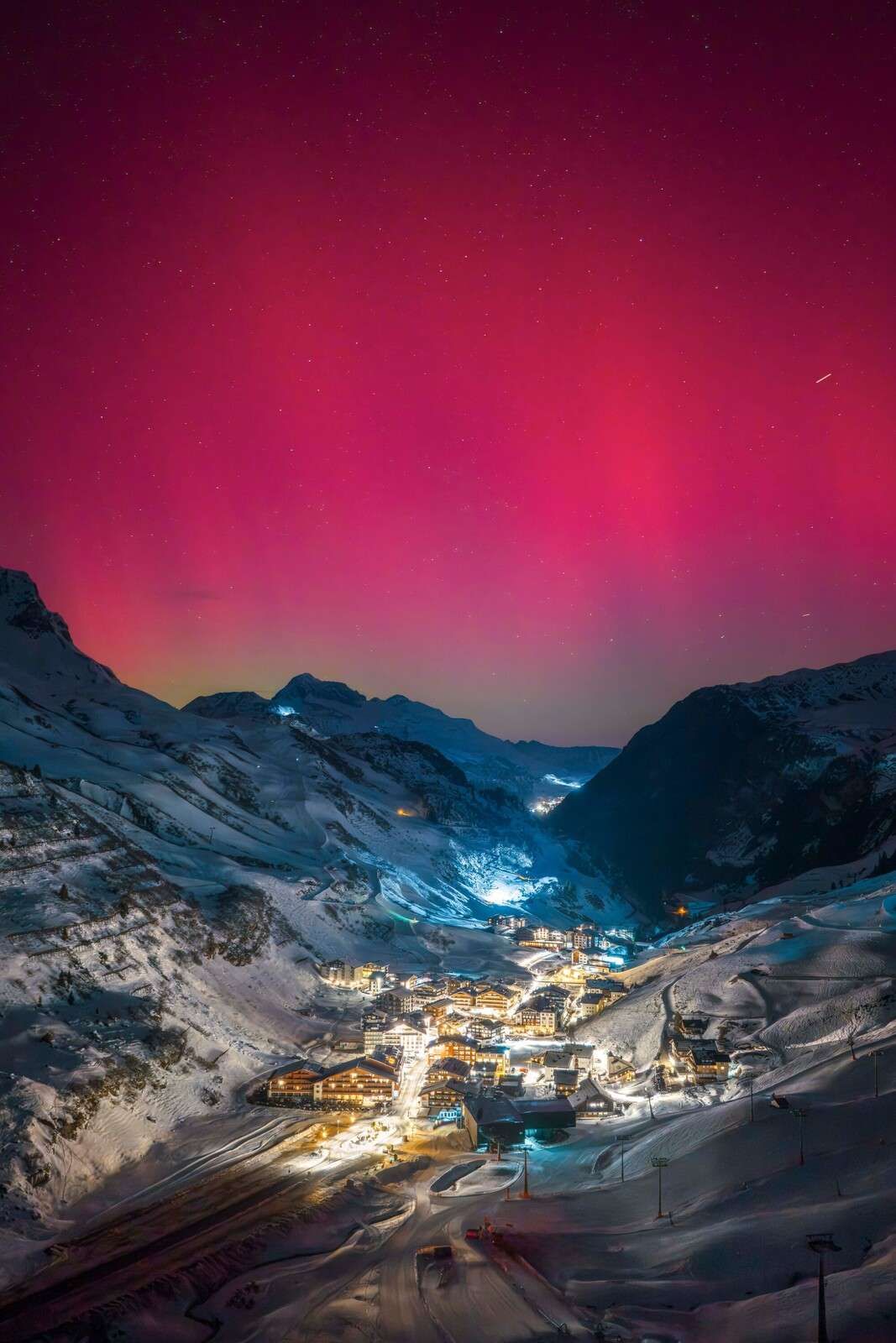 Pink northern lights above mountain village